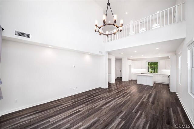 102 Anthology, Irvine, CA 92618 - unfurnished living room featuring dark wood-type flooring, a high ceiling, a chandelier, baseboards, and recessed lighting