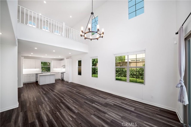 102 Anthology, Irvine, CA 92618 - unfurnished living room featuring a chandelier, a high ceiling, dark wood-style flooring, and baseboards