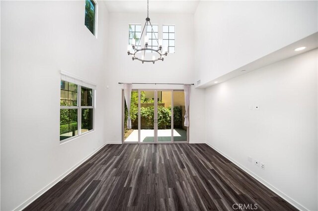 102 Anthology, Irvine, CA 92618 - unfurnished living room with a chandelier, dark wood-style floors, baseboards, and a towering ceiling