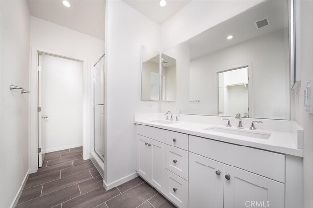 102 Anthology, Irvine, CA 92618 - bathroom with double vanity, baseboards, recessed lighting, a shower with door, and wood finish floors