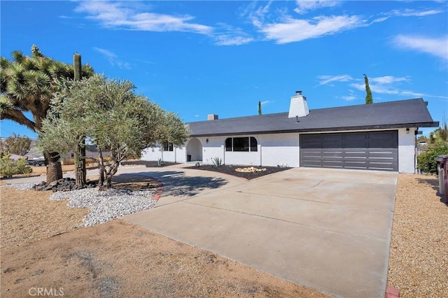 7495 Balsa Ave, Yucca Valley, CA 92284 - view of front of house with driveway, an attached garage, stucco siding, and a chimney