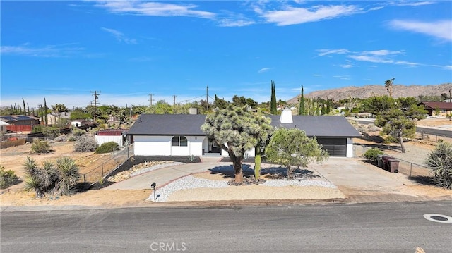 7495 Balsa Ave, Yucca Valley, CA 92284 - view of property hidden behind natural elements with concrete driveway, a mountain view, and an attached garage