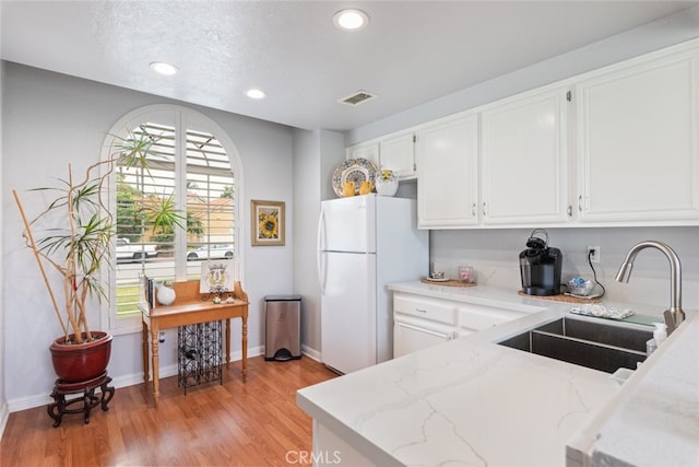 40280 Mimulus Way, Temecula, CA 92591 - kitchen with a sink, freestanding refrigerator, white cabinetry, light wood-style flooring, and light stone countertops