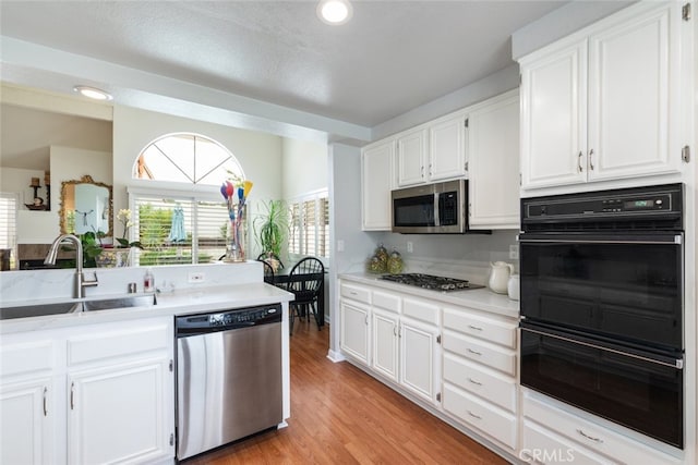 40280 Mimulus Way, Temecula, CA 92591 - kitchen with stainless steel appliances, a sink, white cabinets, light countertops, and light wood-style flooring