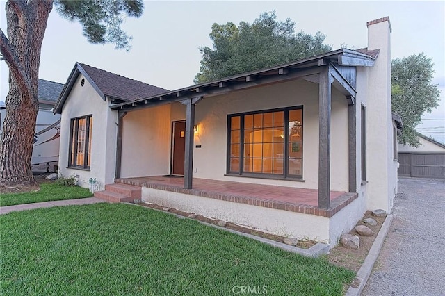 550 N 1st Ave, Upland, CA 91786 - view of front facade featuring a porch, a front lawn, stucco siding, a chimney, and a shingled roof