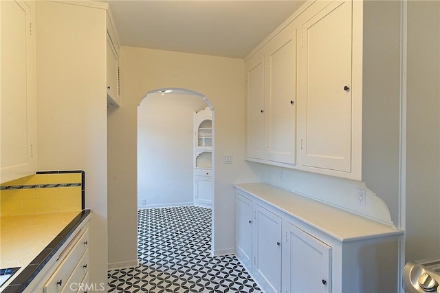 550 N 1st Ave, Upland, CA 91786 - kitchen featuring baseboards, light countertops, arched walkways, and white cabinets