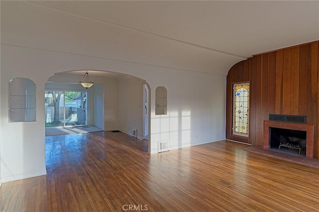 550 N 1st Ave, Upland, CA 91786 - unfurnished living room featuring wood finished floors, arched walkways, vaulted ceiling, a fireplace with raised hearth, and baseboards