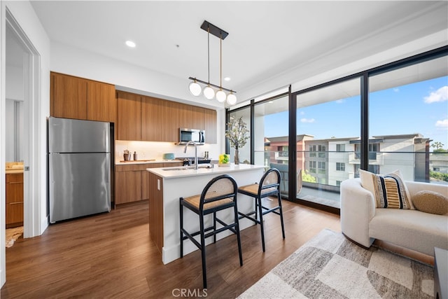 709 E Walnut St Unit 415, Pasadena, CA 91101 - kitchen with stainless steel appliances, brown cabinetry, light countertops, dark wood-type flooring, and an island with sink