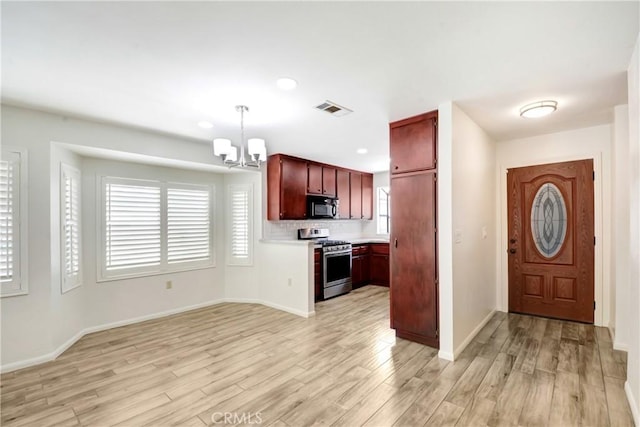 27057 Rangewood St, Menifee, CA 92586 - kitchen with stainless steel range with gas cooktop, black microwave, a chandelier, light wood-style flooring, and light countertops