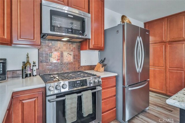 240 Portal St, Oak View, CA 93022 - kitchen featuring appliances with stainless steel finishes, light wood-style flooring, light countertops, tasteful backsplash, and brown cabinets