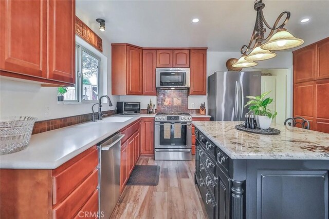 240 Portal St, Oak View, CA 93022 - kitchen featuring appliances with stainless steel finishes, a sink, light wood-style floors, light stone countertops, and decorative light fixtures
