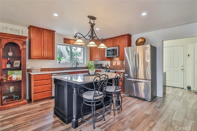 240 Portal St, Oak View, CA 93022 - kitchen with stainless steel appliances, brown cabinetry, light wood finished floors, pendant lighting, and a center island