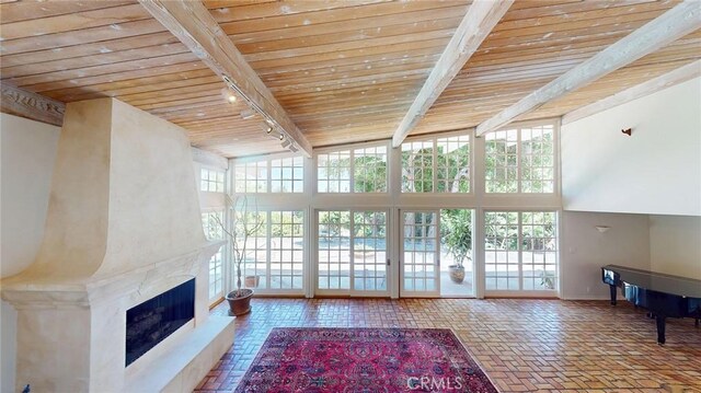 12 Pinto Ln, Rolling Hills Estates, CA 90274 - unfurnished living room featuring a wood ceiling with exposed beams, healthy amount of natural light, track lighting, a fireplace, and brick flooring