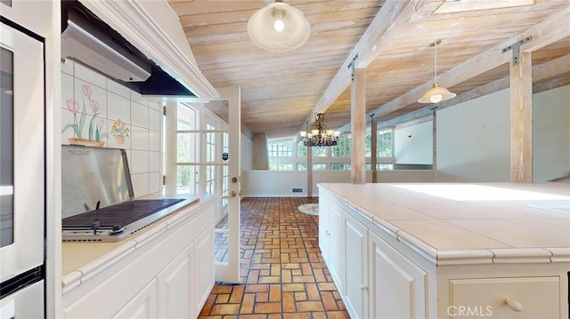 12 Pinto Ln, Rolling Hills Estates, CA 90274 - kitchen featuring brick floors, tile counters, wooden ceiling, white cabinetry, and a chandelier