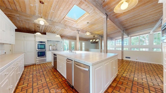 12 Pinto Ln, Rolling Hills Estates, CA 90274 - kitchen featuring appliances with stainless steel finishes, a wood ceiling with exposed beams, a warming drawer, tile countertops, and brick floors