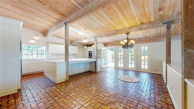 12 Pinto Ln, Rolling Hills Estates, CA 90274 - kitchen with a wood ceiling with exposed beams, a chandelier, light countertops, brick flooring, and white cabinetry