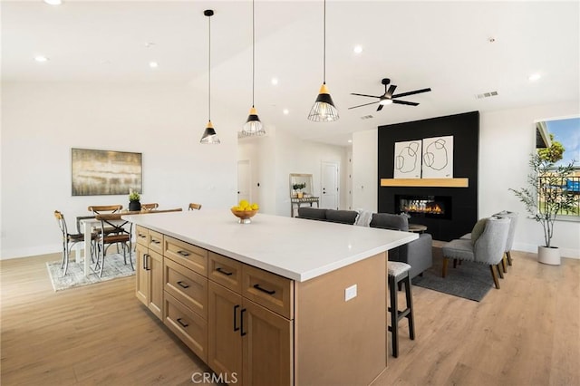 1773 Drendel Cir, Paradise, CA 95969 - kitchen with a center island, light wood-style floors, a kitchen breakfast bar, light countertops, and a fireplace