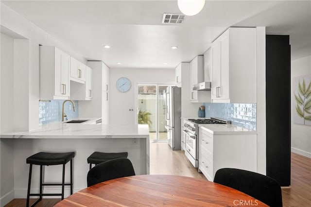 2310 Vanderbilt Ln Unit 4, Redondo Beach, CA 90278 - kitchen featuring appliances with stainless steel finishes, a breakfast bar area, a peninsula, light stone counters, and light wood finished floors