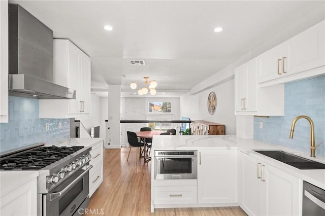 2310 Vanderbilt Ln Unit 4, Redondo Beach, CA 90278 - kitchen with stainless steel appliances, wall chimney exhaust hood, a peninsula, white cabinetry, and backsplash