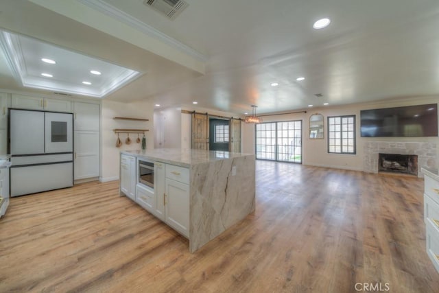 1043 Meadowview Ct, Corona, CA 92878 - kitchen with a barn door, fridge, crown molding, open floor plan, and white cabinetry