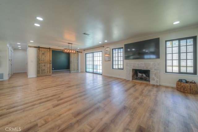 1043 Meadowview Ct, Corona, CA 92878 - unfurnished living room featuring a barn door, recessed lighting, a stone fireplace, light wood finished floors, and crown molding
