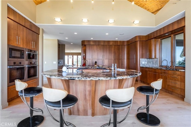 2340 Battering Rock Rd, Templeton, CA 93465 - kitchen with vaulted ceiling, a kitchen bar, brown cabinets, dark stone counters, and a sink