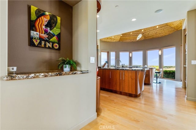 2340 Battering Rock Rd, Templeton, CA 93465 - kitchen with brown cabinets, recessed lighting, light wood-style flooring, baseboards, and dark stone counters