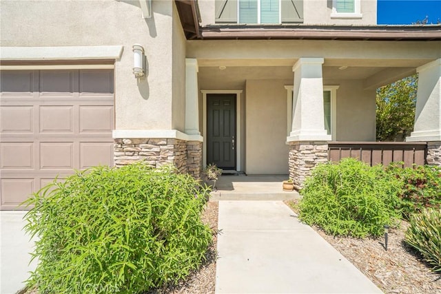 1172 Poinsettia Cir, Calimesa, CA 92320 - view of exterior entry featuring stone siding, stucco siding, a garage, and covered porch