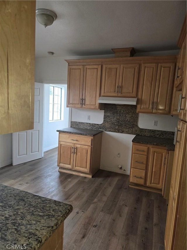 1126 S Dacotah St, Los Angeles, CA 90023 - kitchen featuring under cabinet range hood, dark wood-type flooring, brown cabinets, a textured ceiling, and dark stone countertops