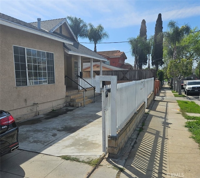 1126 S Dacotah St, Los Angeles, CA 90023 - view of property exterior with stucco siding, a gate, and a shingled roof