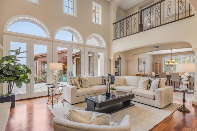 6286 Belmont Trail Ct, San Diego, CA 92130 - living room featuring arched walkways, healthy amount of natural light, a chandelier, a towering ceiling, and wood-type flooring
