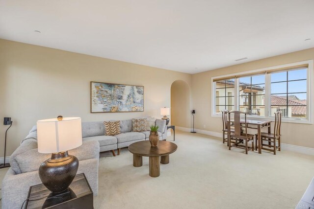 6286 Belmont Trail Ct, San Diego, CA 92130 - living room featuring arched walkways, baseboards, and light carpet