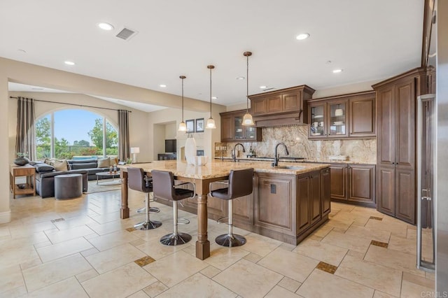 6286 Belmont Trail Ct, San Diego, CA 92130 - kitchen with open floor plan, decorative backsplash, a center island with sink, a kitchen bar, and light stone counters
