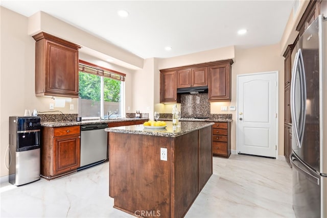 8180 E Brookdale Ln, Anaheim Hills, CA 92807 - kitchen with stainless steel appliances, under cabinet range hood, light marble finish floors, dark stone countertops, and a center island