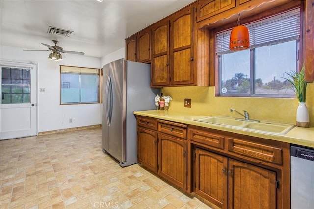 3071 Belle St, San Bernardino, CA 92404 - kitchen with appliances with stainless steel finishes, light countertops, brick patterned flooring, and brown cabinetry