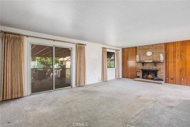 3071 Belle St, San Bernardino, CA 92404 - unfurnished living room featuring healthy amount of natural light, carpet floors, wood walls, and a large fireplace