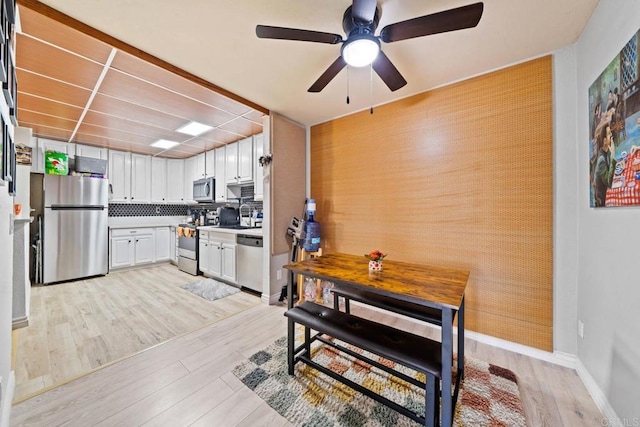 1845 Bayview Heights Dr Unit 110, San Diego, CA 92105 - kitchen featuring stainless steel appliances, light wood-style floors, a ceiling fan, an accent wall, and white cabinets