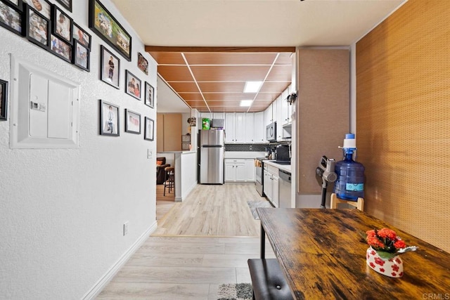 1845 Bayview Heights Dr Unit 110, San Diego, CA 92105 - kitchen featuring appliances with stainless steel finishes, white cabinetry, light wood-style flooring, a textured wall, and light countertops