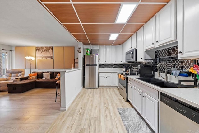 1845 Bayview Heights Dr Unit 110, San Diego, CA 92105 - kitchen with appliances with stainless steel finishes, light wood finished floors, decorative backsplash, and white cabinets