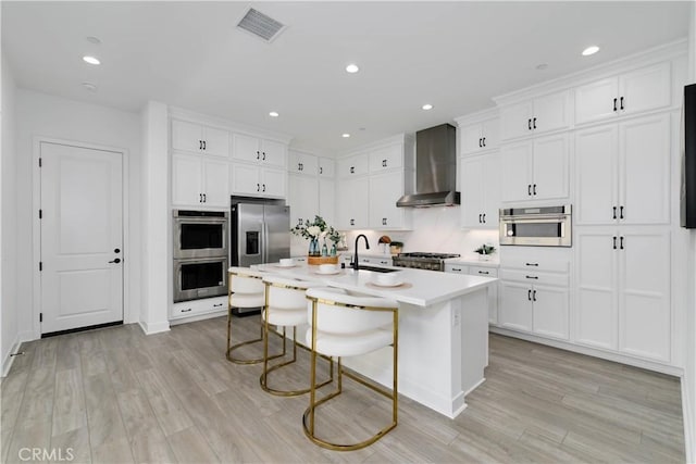 484 Chorus, Irvine, CA 92618 - kitchen with wall chimney exhaust hood, appliances with stainless steel finishes, a sink, a breakfast bar area, and light wood-type flooring