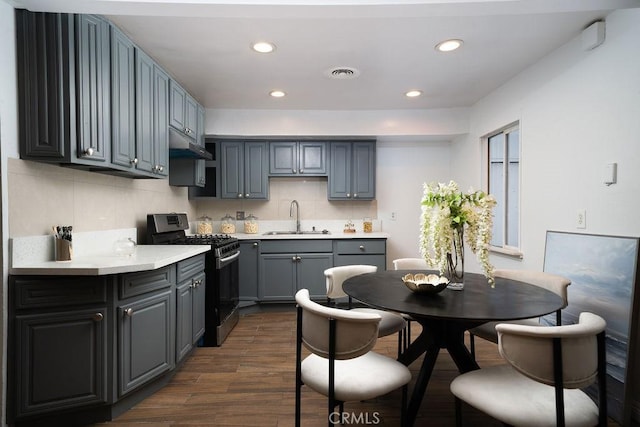 8151 Orangewood Ave, Stanton, CA 90680 - kitchen featuring gas range oven, a sink, dark wood-style flooring, under cabinet range hood, and tasteful backsplash