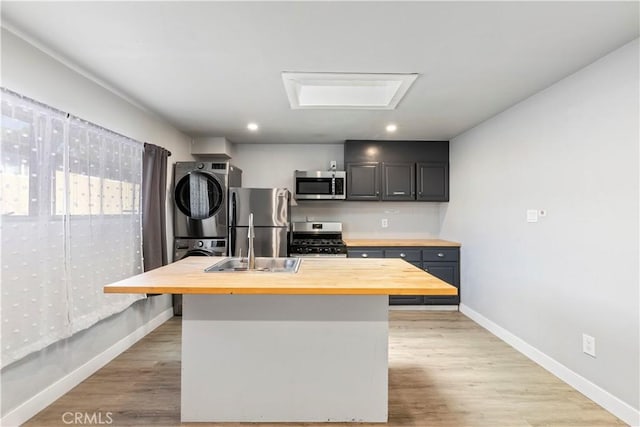 134 Palm Ave, National City, CA 91950 - kitchen with wood counters, appliances with stainless steel finishes, stacked washer / dryer, baseboards, and recessed lighting