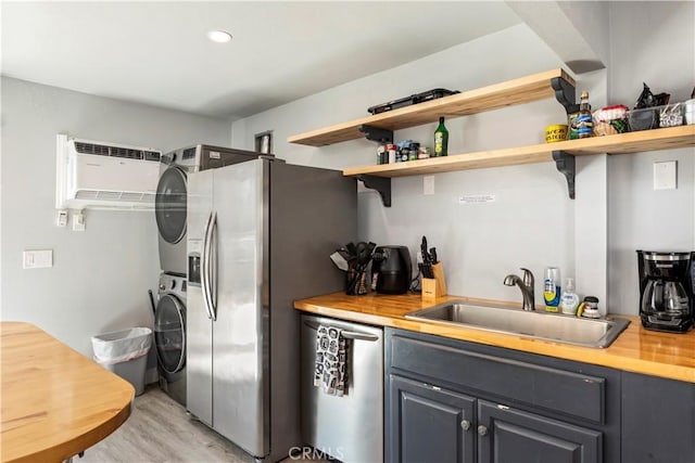 134 Palm Ave, National City, CA 91950 - kitchen with stacked washer and clothes dryer, a sink, appliances with stainless steel finishes, light wood finished floors, and open shelves