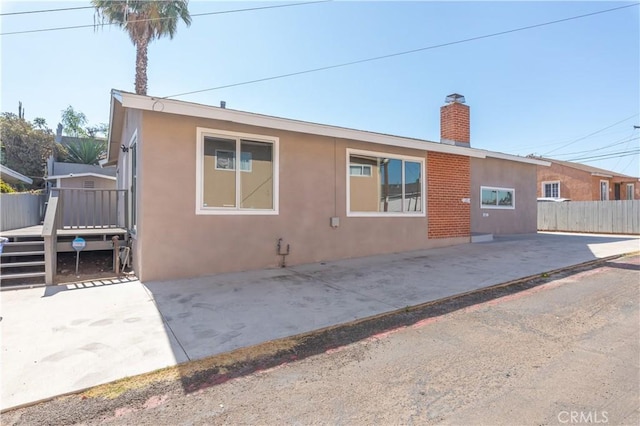 134 Palm Ave, National City, CA 91950 - back of house with a wooden deck, a chimney, stucco siding, and a patio area