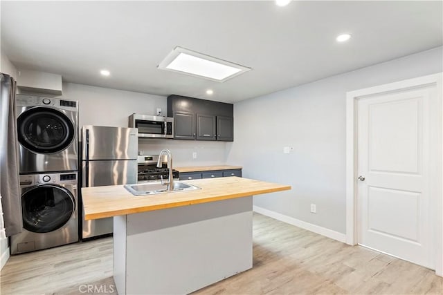 134 Palm Ave, National City, CA 91950 - kitchen featuring wood counters, stacked washer / dryer, stainless steel appliances, light wood finished floors, and baseboards