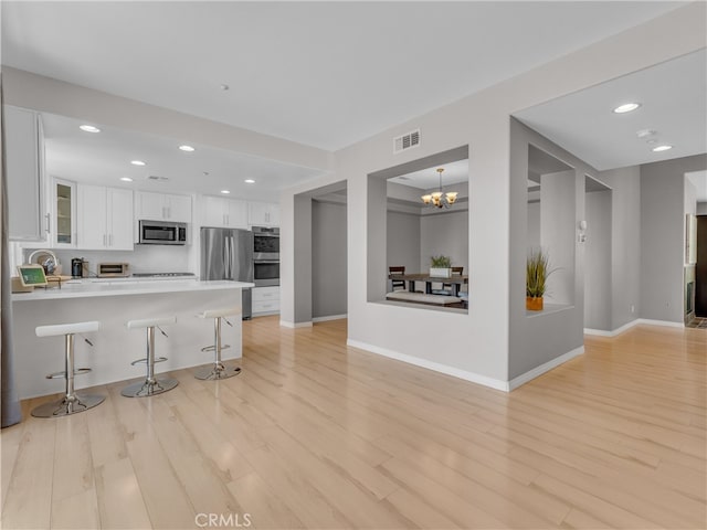 5637 Como Cir, Woodland Hills, CA 91367 - kitchen featuring appliances with stainless steel finishes, a breakfast bar area, white cabinets, light wood-style floors, and recessed lighting
