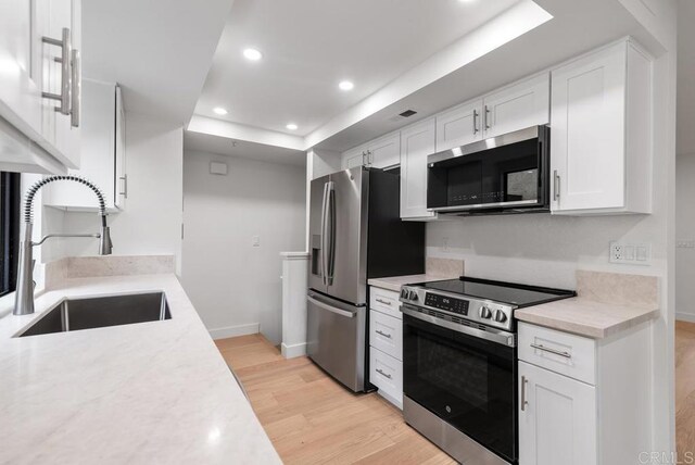 1680 N Coast Highway 101 Unit 36, Encinitas, CA 92024 - kitchen featuring appliances with stainless steel finishes, a raised ceiling, light wood-style floors, light countertops, and recessed lighting