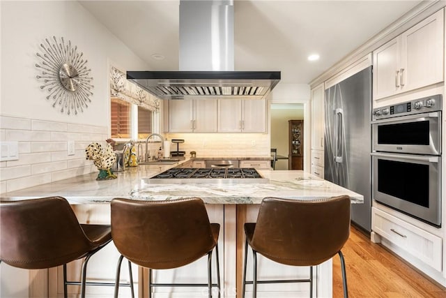 2902 E Trenton E, Orange, CA 92867 - kitchen featuring wall chimney range hood, appliances with stainless steel finishes, a peninsula, light stone countertops, and decorative backsplash
