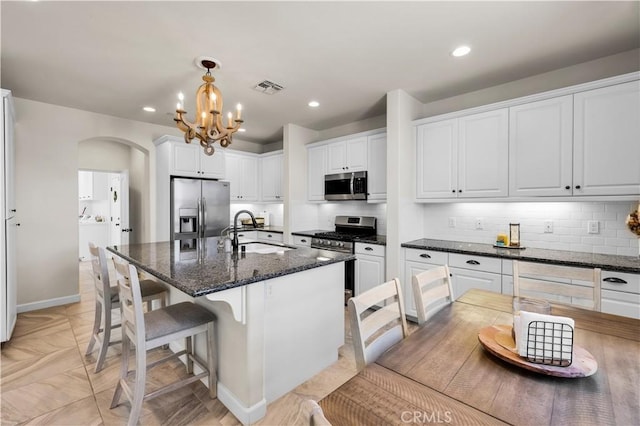 7988 Borrego Ct, Yucca Valley, CA 92284 - kitchen with stainless steel appliances, a sink, arched walkways, white cabinetry, and decorative backsplash