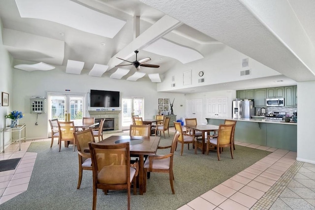 3376 Corsica Way, Oceanside, CA 92056 - dining space with light tile patterned floors, a glass covered fireplace, a ceiling fan, and high vaulted ceiling
